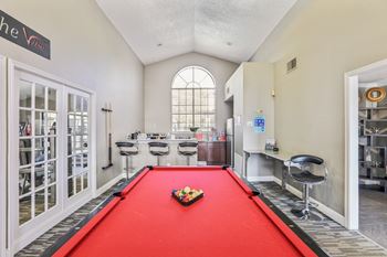 A pool table with a red cloth and a set of pool balls in the middle.